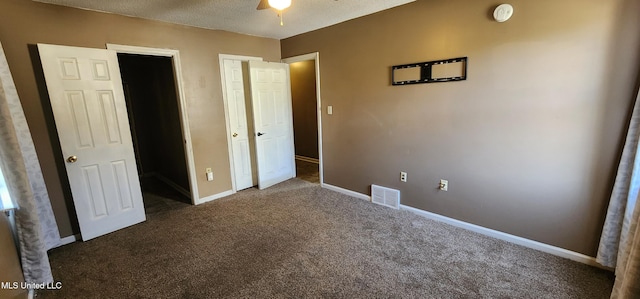 unfurnished bedroom featuring ceiling fan, a textured ceiling, visible vents, carpet floors, and baseboards