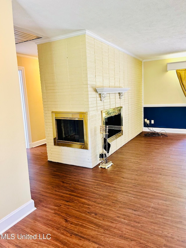 unfurnished living room with ornamental molding, a textured ceiling, a fireplace, and wood-type flooring