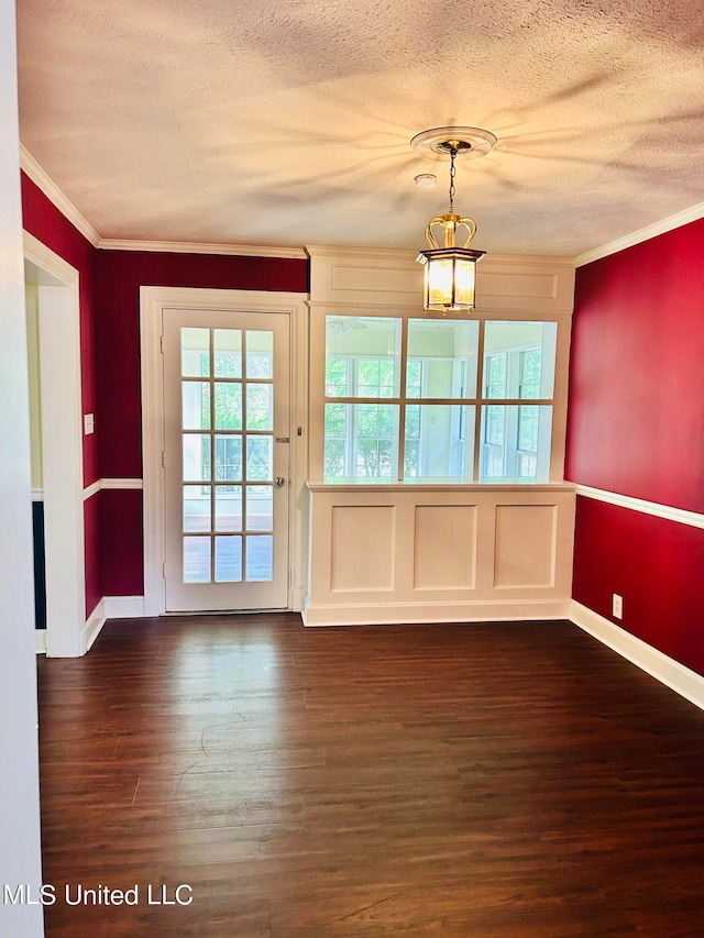 spare room featuring a textured ceiling, ornamental molding, dark hardwood / wood-style floors, and an inviting chandelier