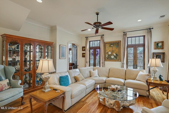 living room featuring a wealth of natural light, light hardwood / wood-style flooring, crown molding, and french doors