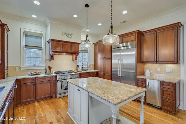 kitchen featuring a kitchen bar, decorative light fixtures, light stone countertops, and premium appliances