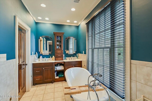 bathroom featuring tile walls, ornamental molding, vanity, a bathtub, and tile patterned flooring