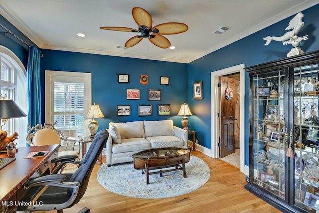 living room featuring ceiling fan, ornamental molding, and light hardwood / wood-style flooring