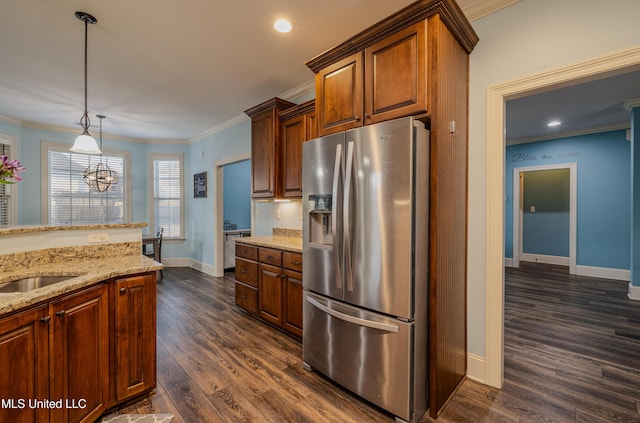 kitchen with light stone countertops, stainless steel fridge, dark wood finished floors, decorative light fixtures, and crown molding