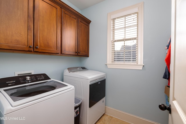 washroom featuring baseboards, cabinet space, and washer and dryer