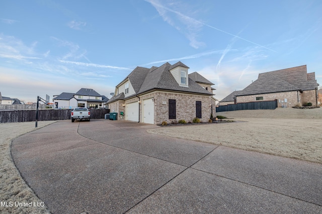 view of side of property with concrete driveway, a residential view, roof with shingles, fence, and brick siding