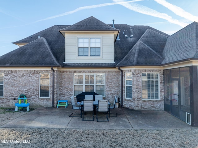 rear view of property featuring a shingled roof and a patio