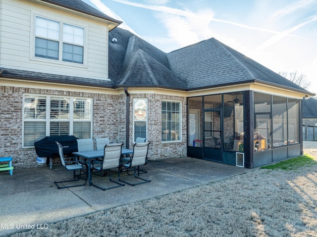 rear view of property with a patio, brick siding, a shingled roof, and a sunroom