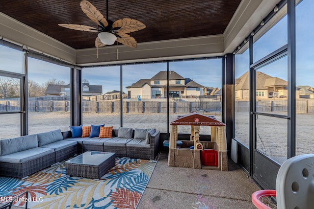 sunroom with a ceiling fan, a residential view, and a healthy amount of sunlight