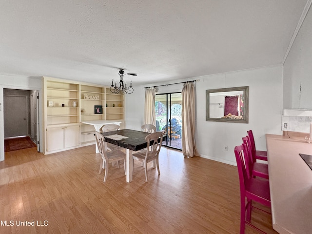 dining space with light hardwood / wood-style floors, a textured ceiling, and a chandelier