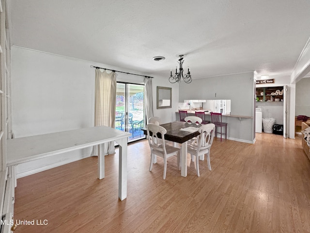 dining room featuring hardwood / wood-style flooring, washer / dryer, ornamental molding, an inviting chandelier, and a textured ceiling