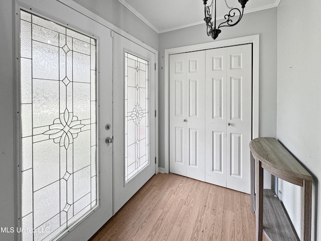 foyer entrance with french doors, a notable chandelier, ornamental molding, and light hardwood / wood-style flooring