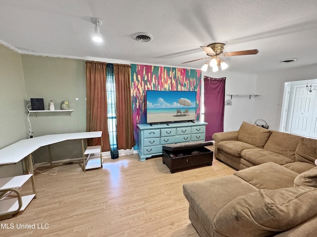 living room with ceiling fan, a textured ceiling, and light wood-type flooring