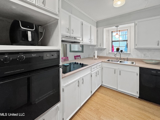 kitchen featuring black appliances, sink, pendant lighting, white cabinets, and light hardwood / wood-style flooring