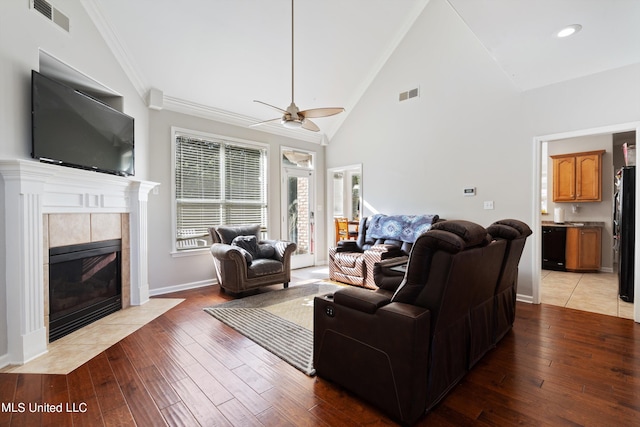 living room with ornamental molding, hardwood / wood-style floors, a fireplace, high vaulted ceiling, and ceiling fan