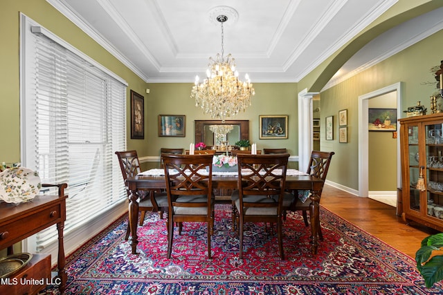 9194 Rosalie Cv, Olive Branch, MS 38654 - dining area featuring wood finished floors, a tray ceiling, a chandelier, ornamental molding, and ornate columns