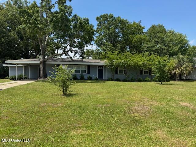 318 E 4th St, Long Beach, MS 39560 - view of front of home featuring an attached carport, a front lawn, and driveway