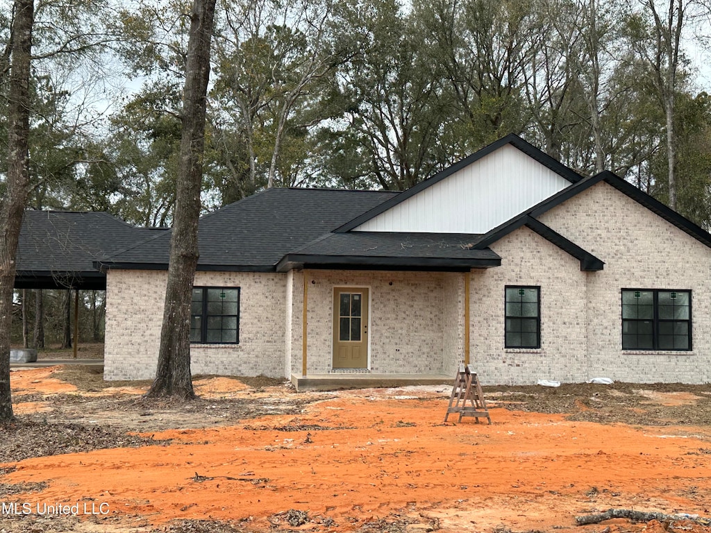 view of front facade featuring brick siding and roof with shingles