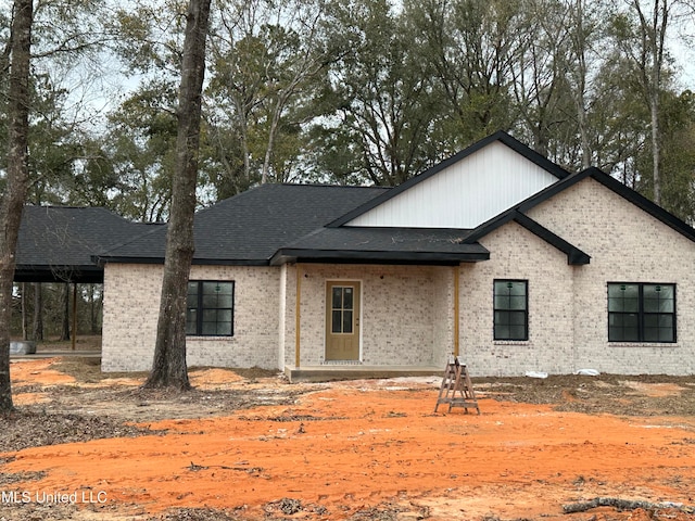 view of front facade featuring brick siding and roof with shingles