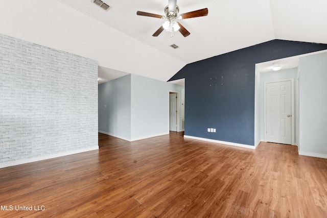 interior space featuring ceiling fan, brick wall, vaulted ceiling, and hardwood / wood-style flooring