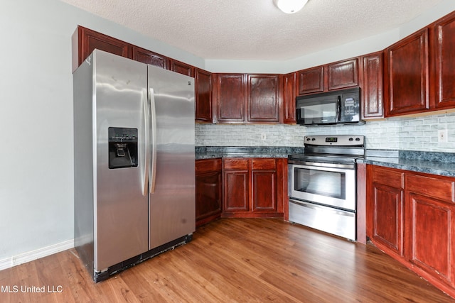 kitchen featuring decorative backsplash, light hardwood / wood-style flooring, a textured ceiling, and appliances with stainless steel finishes