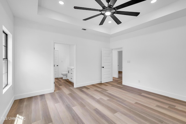 unfurnished bedroom with recessed lighting, a raised ceiling, and light wood-style flooring