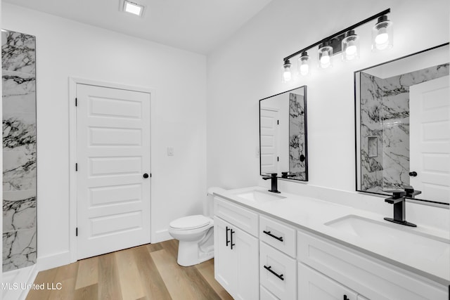 bathroom featuring wood finished floors, toilet, a marble finish shower, and a sink