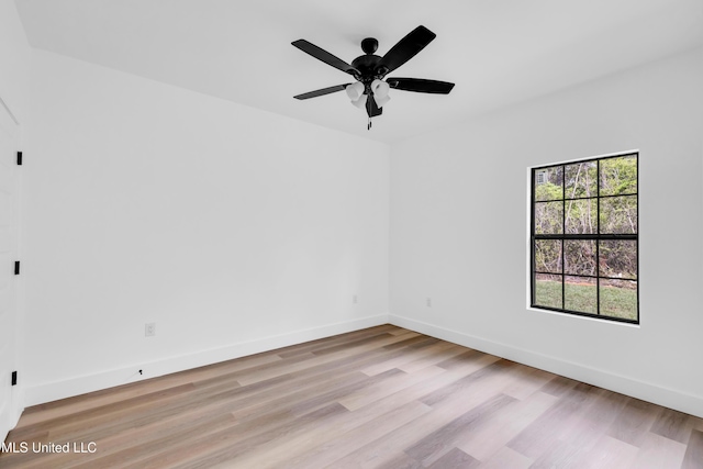 spare room with light wood finished floors, a ceiling fan, and baseboards