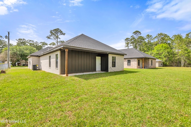 back of property featuring a yard, a shingled roof, board and batten siding, and brick siding
