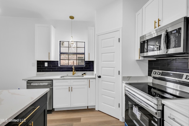 kitchen featuring appliances with stainless steel finishes, white cabinetry, backsplash, and a sink