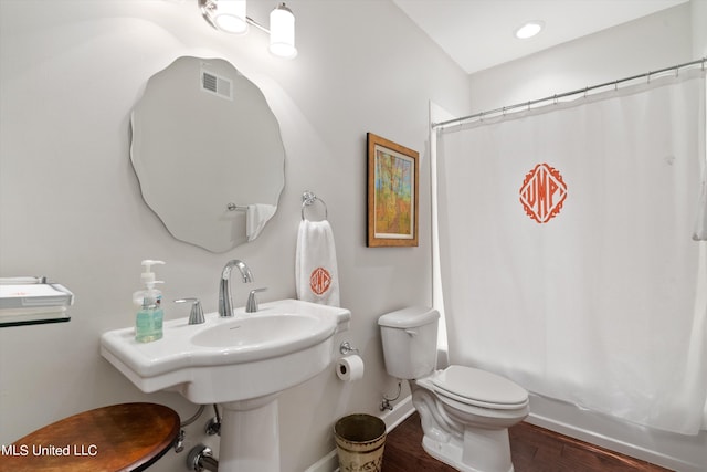 bathroom with toilet, baseboards, visible vents, shower / tub combo with curtain, and wood finished floors