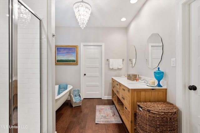 bathroom featuring a shower stall, wood finished floors, vanity, a freestanding bath, and recessed lighting