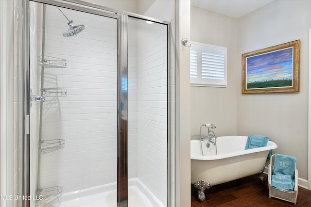bathroom featuring a freestanding bath, wood finished floors, baseboards, and a stall shower