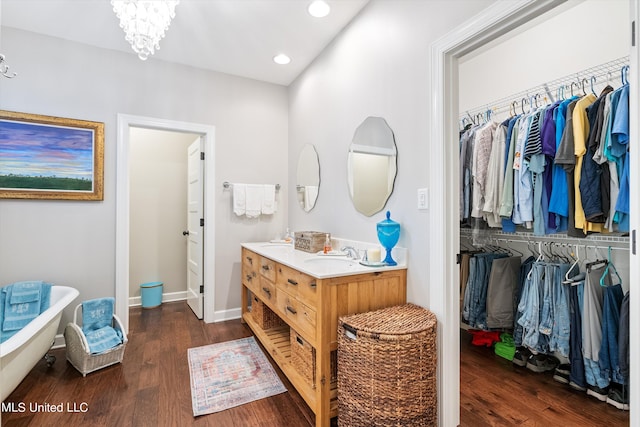 bathroom featuring a soaking tub, double vanity, a spacious closet, recessed lighting, and wood finished floors