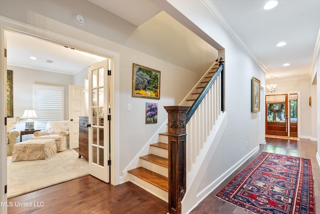 stairs with a notable chandelier, wood-type flooring, and ornamental molding