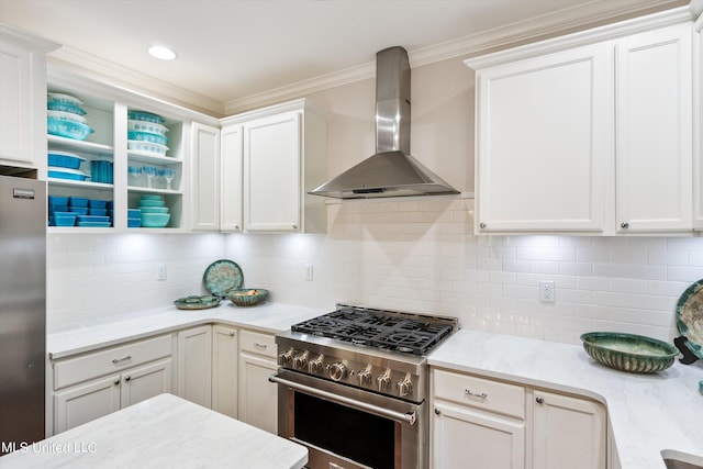 kitchen featuring wall chimney range hood, decorative backsplash, stainless steel appliances, and white cabinets