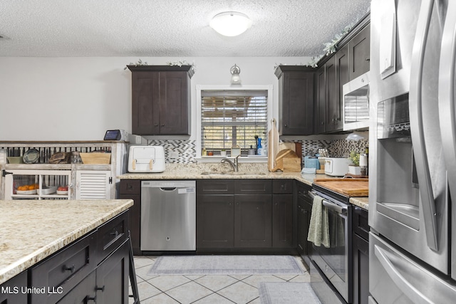 kitchen featuring sink, decorative backsplash, stainless steel appliances, and a textured ceiling