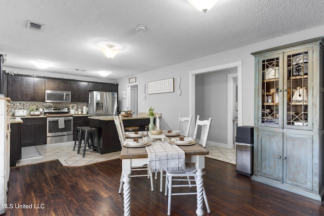 dining space featuring a textured ceiling and dark hardwood / wood-style flooring