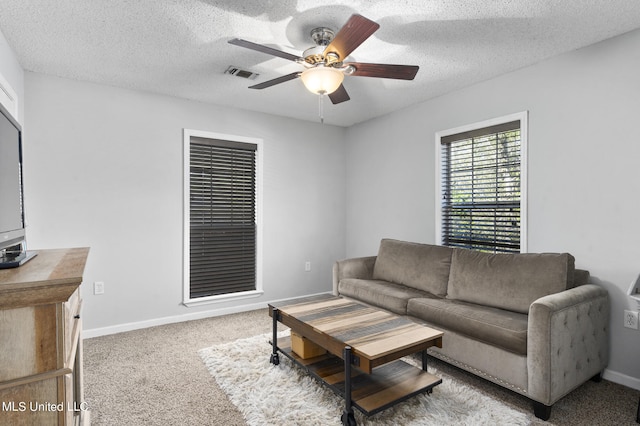 living room with a textured ceiling, carpet floors, and ceiling fan