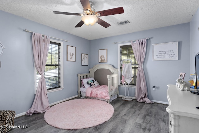 bedroom with multiple windows, hardwood / wood-style floors, a textured ceiling, and ceiling fan