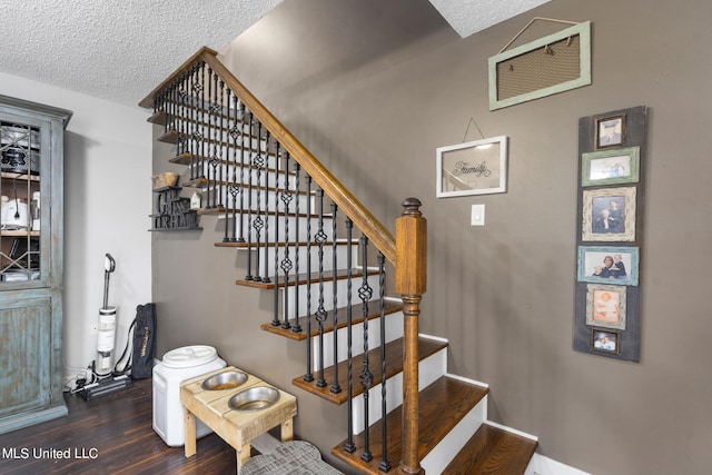 staircase with a textured ceiling and wood-type flooring