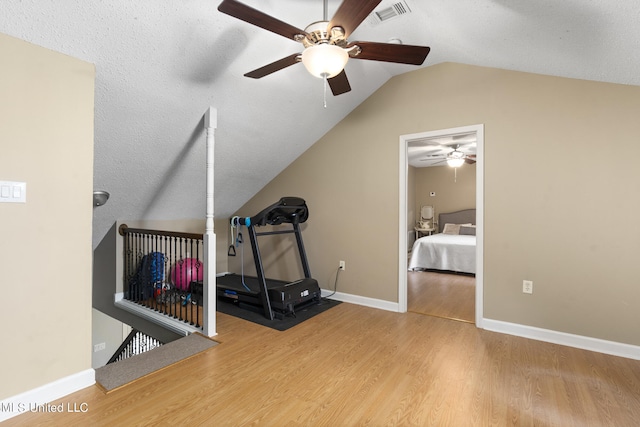 workout area with lofted ceiling, hardwood / wood-style floors, a textured ceiling, and ceiling fan