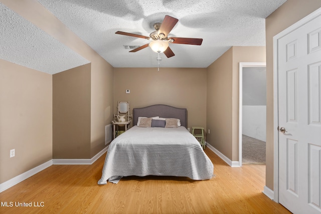 bedroom featuring a textured ceiling, wood-type flooring, and ceiling fan