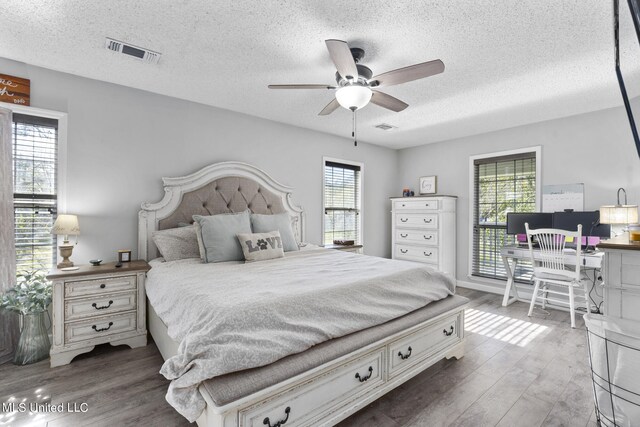 bedroom featuring a textured ceiling, dark hardwood / wood-style floors, and ceiling fan