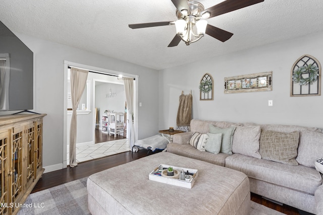 living room with dark wood-type flooring, a textured ceiling, and ceiling fan