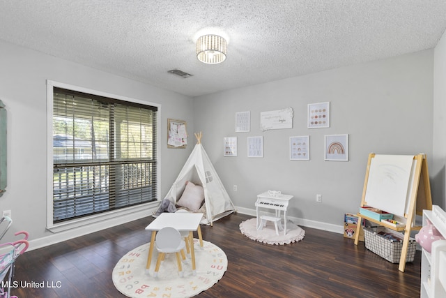 playroom with dark wood-type flooring and a textured ceiling