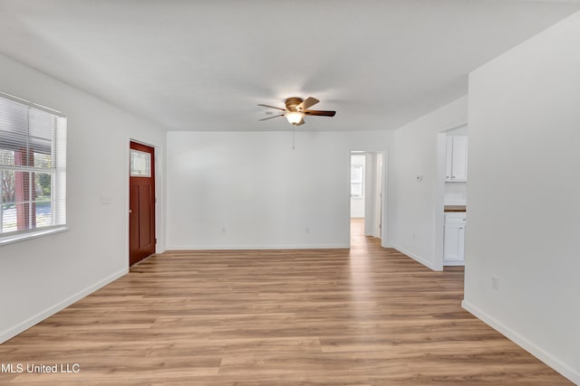 unfurnished living room with light wood-style flooring, baseboards, and ceiling fan