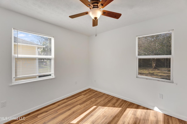 empty room featuring ceiling fan, light wood finished floors, and baseboards