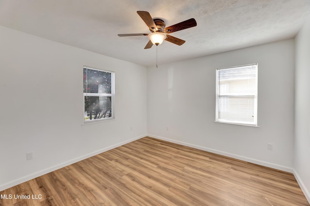 unfurnished room with a textured ceiling, light wood finished floors, a ceiling fan, and baseboards