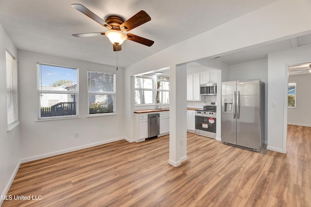 kitchen with stainless steel appliances, light wood-style floors, a healthy amount of sunlight, and white cabinets